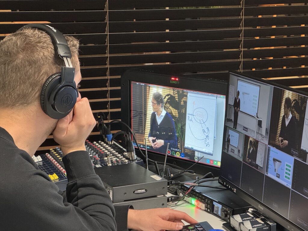 Production d'une vidéo : depuis la régie, un technicien suit l'enregistrement d'une session au tableau blanc.